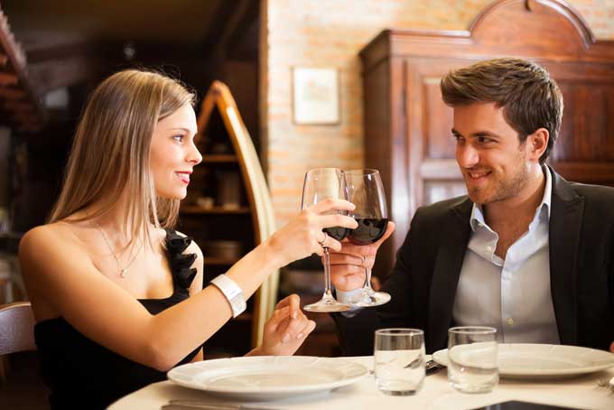 a couple clinking wine glasses on their first date at a restaurant